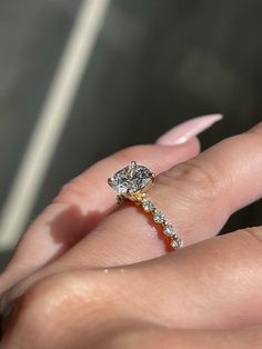 a woman's hand with a diamond ring on top of her finger and pink fingernails