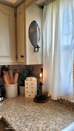 a kitchen counter top with some candles and other items on it in front of a window