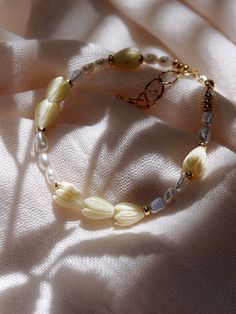 "Inspired by traditional Hawaiian leis gifted as tokens of hospitality, this handmade gold and pearl bracelet features a glistening collection of pearls, gold beads and pikake flower blossoms. Stack this gold pearl bracelet with other beaded beauties and you'll be ready for your tropical escape. ✦ DETAILS ✦ ✧ Name: Mele (MEH-leh) - Song. ✧ Adjustable Length from: 6.5\"-8\". ✧ 3-4mm Freshwater Pearl Beads. ✧ Carved Resin Pikake Beads ✧ 14kt Gold Filled Components, Extender, and Clasp. ✧ All Ke Al Cream Jewelry With Large Beads As A Gift, Cream Jewelry With Large Beads For Gift, Bohemian Single Strand Beaded Bracelets As Gift, Elegant Yellow Flower Bracelets, Elegant Yellow Flower Bracelet, Handmade Cream Pearl Bracelet With Round Beads, Adjustable Pearl Bracelet With Large Beads As Gift, Elegant Tiny Beads Bracelet For Beach, Flower Shaped Single Strand Jewelry For Gifts