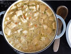 a pot filled with chicken and broth next to two plates