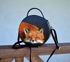 This round leather bag with a hand-painted cute Fox art is very bright and elegant. The miniature crossbody bag has a removable shoulder strap. This is a tiny circle purse with an orange woodland Fox. The functional elements give the whole a refined note of elegance, while the particular capacity and two separate compartments turn it into a must-have for everyday use. The crossbody box bag is perfect for a casual look, fashionable and trendy. The black circular bag is made from genuine embossed Cute Fox Art, Fox Clothes, Fox Purse, Circle Purse, Woodland Fox, Travel Purse, Top Handle Bags, Fox Art, Round Leather