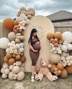 a pregnant woman standing in front of a backdrop made out of balloons and teddy bears