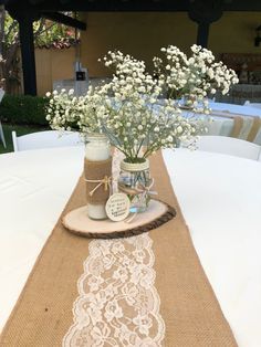 mason jar vases with baby's breath flowers on a burlock table runner