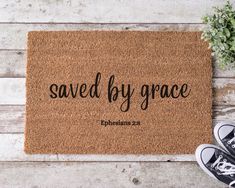 a door mat with the words saved by grace on it next to a pair of sneakers