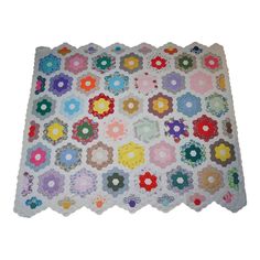 a multicolored quilt on a white surface with many different flowers in the center