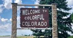 the welcome sign to colorful colorado is posted in front of a road with trees and grass