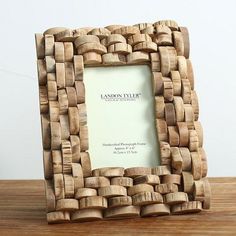 a wooden photo frame made out of wine corks on a table with a white wall in the background