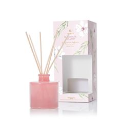 a pink candle and reed diffuser in front of a white box with flowers on it