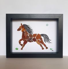 a horse made out of rocks in a black frame