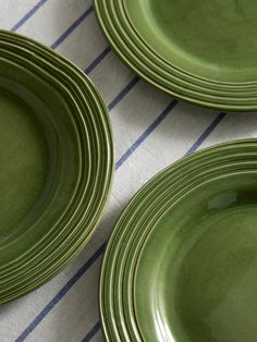 three green plates sitting on top of a blue and white table cloth