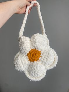 a crocheted white bag with an orange center hanging from it's side