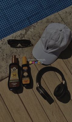 various items laid out on the ground next to a pool with sunglasses, hat and sunscreen