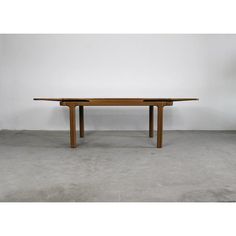 a wooden table sitting on top of a cement floor next to a white wall in a room