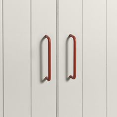 two red handles on white cupboards in a room with wood flooring and white walls