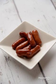 a white square bowl filled with hot dogs