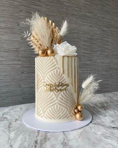 a white and gold cake with feathers on top