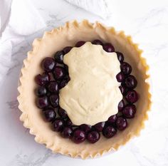 a tart dish with grapes and cream in it on a marble counter top, ready to be eaten