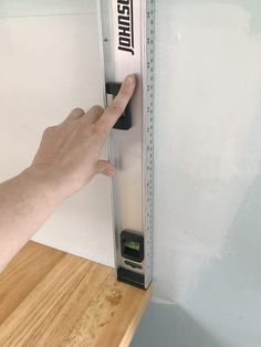 a hand is pointing at a ruler on the wall