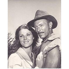 an old black and white photo of a man and woman posing for the camera with their arms around each other