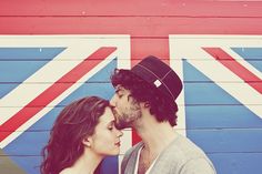 a man and woman standing next to each other in front of a wall with the british flag painted on it