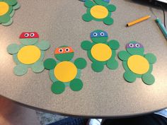 paper cut out of turtles sitting on top of a table with pencils and markers