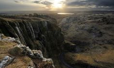 the sun is setting over a canyon with a winding road on it's side