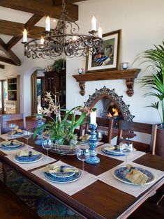 the dining room table is set with blue and white plates, place settings, and candles