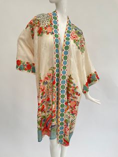 "This lovely antique 1930s Japanese export silky rayon robe is in a rare cream colour with soft complementary highlight colours including blue orange, green and white. It is a classic of its type, having a detailed design of flowers, a bridge and pagodas in a landscape. There are no ties, so this robe is designed to be worn open. I particularly like the unusual repeating geometric circle design on the front edges of this robe.  This is a free sized garment so will fit a variety of sizes. When laid flat, the length is approximately 40\" inches and from underarm to underarm across is approximately 25\" inches.  The condition is excellent overall, this looks to have hardly been worn and the colours are fresh and bright. On close inspection I can see a feint mark line to the front which I susp Traditional White Robe With Kimono Sleeves, Traditional White Robe For Spring, Vintage White Daywear Robe, Vintage Long Summer Robe, White Kimono With Floral Embroidery, Vintage Multicolor Spring Kimono, Vintage White Robe For Daywear, White Long Silk Kimono, Long Cream Spring Kimono