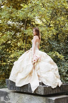 a woman in a wedding dress sitting on a stone bench