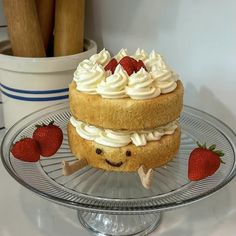 a cake sitting on top of a glass platter covered in frosting and strawberries