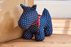 a blue dog stuffed animal sitting next to a wooden door