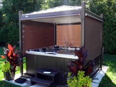 an outdoor hot tub in the middle of some grass and trees with brown shades on it