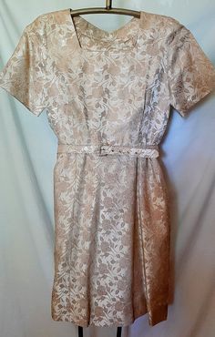 There are no labels on this dress.  Classic 50s style dress in excellent condition.   Fabric is sleek with a brocade flower pattern in a gold tone.  Very pretty.  Has a belt.  Armpit to armpit is 18 inches.  Waist is 33 inches.  Skirt is a fuller a-line.  Length is 23 inches from the waist.  Sale is final. Gold Short Sleeve Formal Dress, Elegant Short Sleeve Gold Dresses, Elegant Gold Dress With Short Sleeves, Elegant Gold Dresses With Short Sleeves, Fitted Short Sleeve Dress For Vintage Events, Elegant Fitted Vintage Dress With Short Sleeves, Classic Short Sleeve Dress For Vintage Events, Classic Short Sleeve Vintage Evening Dress, Classic Vintage Dress With Short Sleeves For Evening