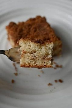 a piece of cake on a white plate with a fork in the foreground and a bite taken out of it