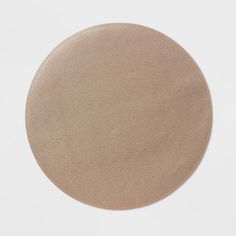 a round beige leather coaster on a white surface with no one in the room around it