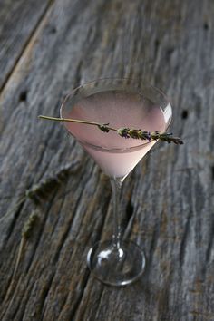 a martini glass filled with pink liquid and garnished with lavender sprigs