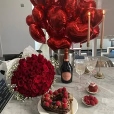 a table topped with red roses and chocolates next to a heart - shaped balloon