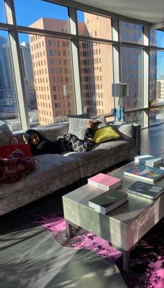 a living room filled with furniture and large windows overlooking the cityscape in the distance