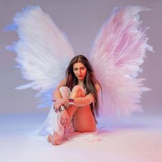 a woman with angel wings sitting on the ground