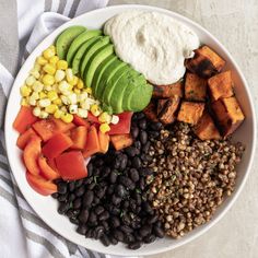 a white plate topped with black beans, avocado, corn and sweet potatoes