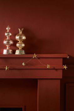 a red fireplace with gold stars on the mantle and two silver vases next to it