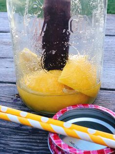 a glass jar filled with liquid next to a yellow and white striped paper plate on top of a wooden table