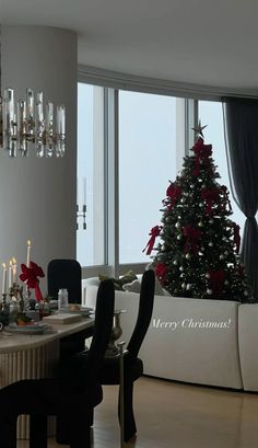 a christmas tree is in the middle of a room with chairs and a dining table