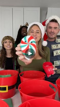 a group of people standing around red buckets with candy cane on top of them