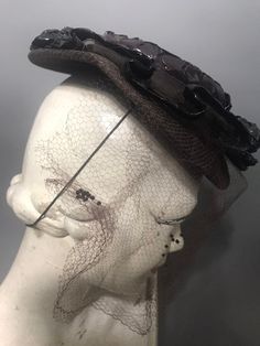 A rather fab 1940s tilt hat with a wonderful long veil. The wired brim is covered with a jersey type fabric and there is a mesh frill on the br with raffia border. The crown is covered in raffia. The hat doesn't have a label. Due to design this is a one size fits all hat and there is an elastic to hold it in place. Vintage Wide Brim Costume Hat For Evening, Vintage Wide Brim Top Hat For Evening, Victorian Cloche Hat For Evening, Vintage Evening Costume Hats And Headpieces For Summer, Victorian Evening Hats For Kentucky Derby, Vintage Costume Hats And Headpieces For Summer Evenings, Vintage Summer Evening Costume Hats And Headpieces, Vintage Adjustable Fascinator With Curved Brim, Adjustable Vintage Fascinator With Curved Brim