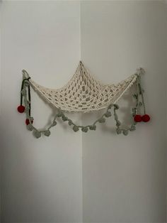 a crocheted hammock hanging on the wall with pom - poms