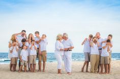 a large group of people standing on top of a sandy beach next to the ocean