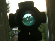 a close up view of a camera lens with trees in the back ground and houses in the background