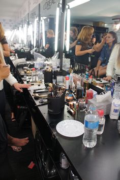 a woman standing in front of a counter filled with makeup