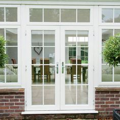 an image of a house that has glass doors and brick wall in the front yard